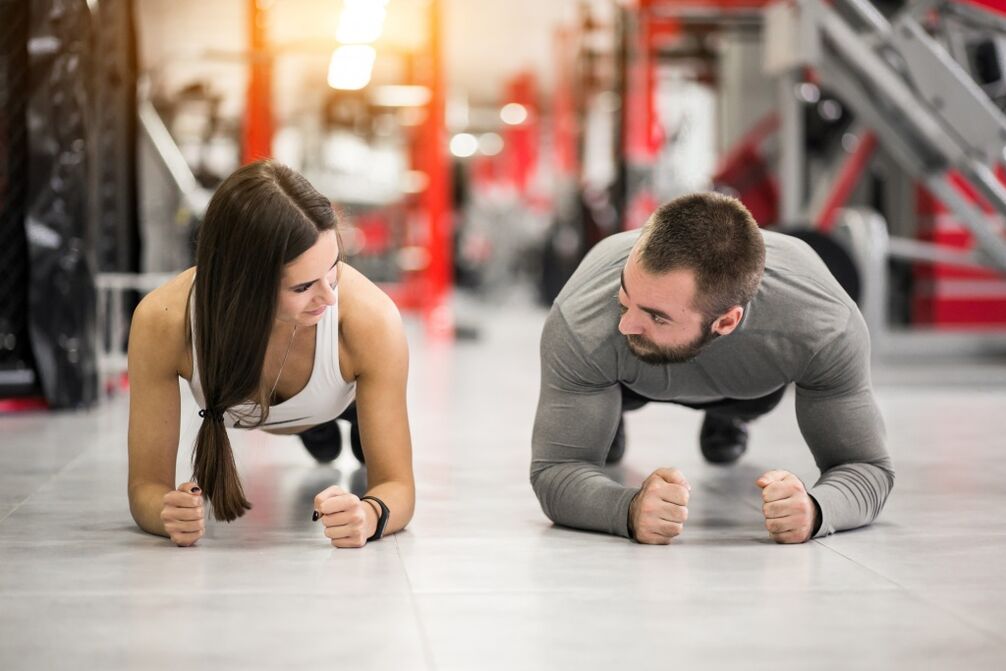 Un bărbat și o femeie efectuează exercițiul Plank, conceput pentru toate grupele musculare